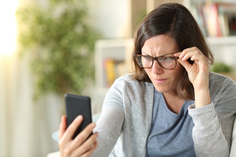 woman having trouble reading smartphone